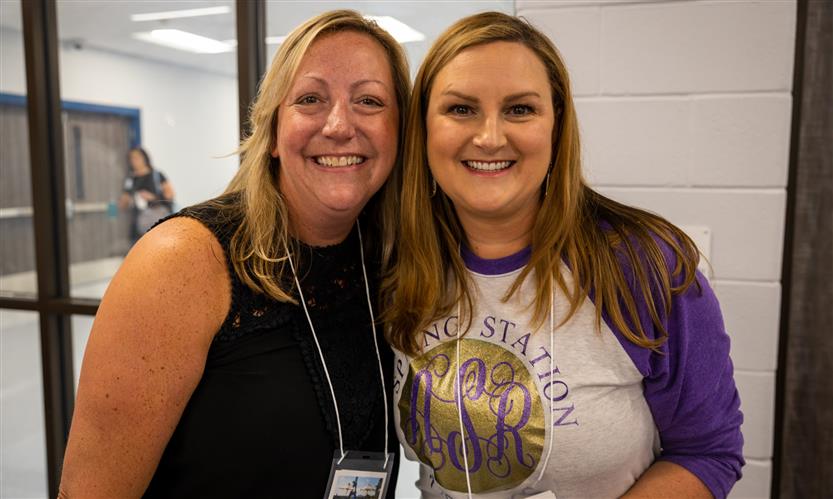 Two administrators stand together and smile